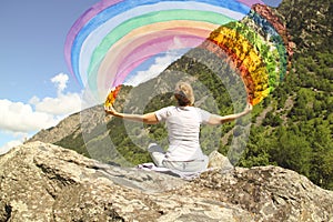 A young girl meditating on a mountaintop with a rainbow