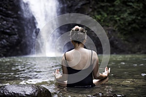 Young girl meditating outdoors in green park on nature background