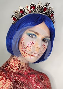 Young girl model in the art make-up like princess in a crown from fairytail looking at camera with blue hair photo