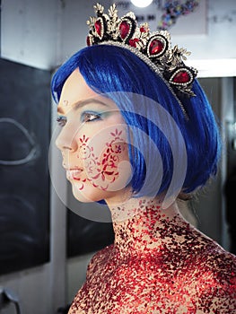 Young girl model in the art make-up like princess in a crown from fairytail view from left side