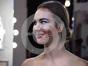 Young girl model in the art make-up like princess with paint at her cheek