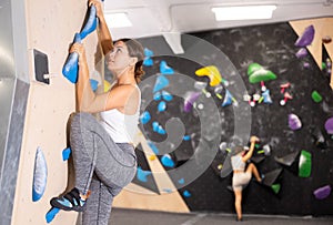 Young girl moving on bouldering wall at indoor climbing gym