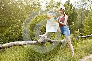 Young girl on nature with hat and map. Summer