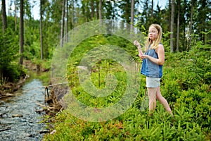 Young girl near cold shallow stream winding through majestic pine trees of Tatra mountain range near Zakopane, Poland