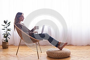 Young girl networking on laptop, relaxing with coffee