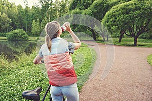 Young girl next to her bike drinking water with a bottle in a park