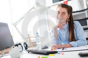 Young girl in the office sits at the computer desk.