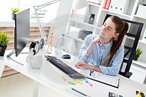 Young girl in the office sits at the computer desk.