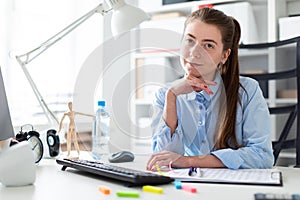 Young girl in the office sits at the computer desk.