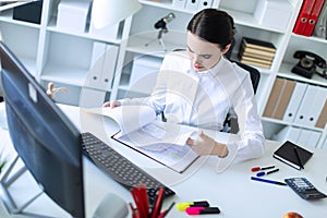 Young girl in the office working with documents at the computer.