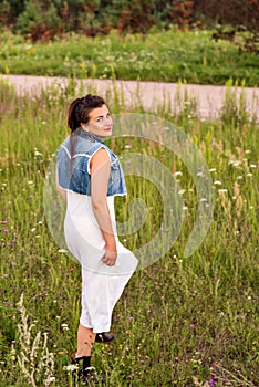 Young girl in old-fashioned clothes is walking in the sunset field