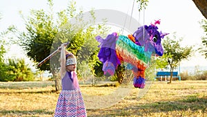 Young girl at an outdoor party hitting a pinata photo