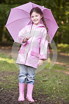 Young girl outdoors with umbrella smiling