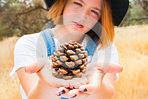 Young Girl in Overalls Holding up a Pinecone