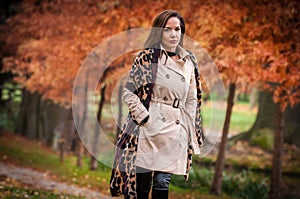 young girl in overcoat in forest. Fashion woman in coat in park. Slim young fashion model wearing white coat outdoor.