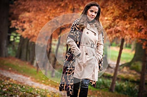 young girl in overcoat in forest. Fashion woman in coat in park. Slim young fashion model wearing white coat outdoor.