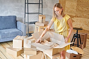 Young girl packing plates into the boxes ready to move. Woman unpacking moving boxes in her new home. unpack personal