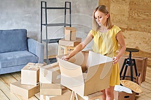 Young girl packing plates into the boxes ready to move. Woman unpacking moving boxes in her new home. unpack personal