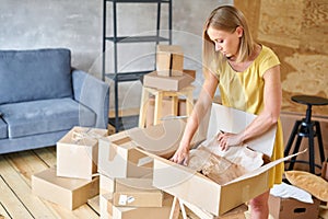 Young girl packing plates into the boxes ready to move. Woman unpacking moving boxes in her new home. unpack personal