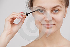A young girl paints her eyelashes with mascara. Face close-up. facial care photo