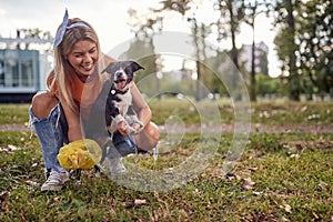 A young girl in the park is having a good time while cleaning up after her dog. Friendship, walk, pets