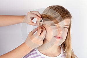 Young girl patient not too happy while hands inserting a hearing