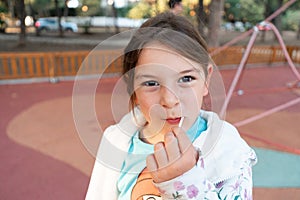 A young girl pauses for a reflective moment with her lollipop, creating a portrait of childhood contemplation