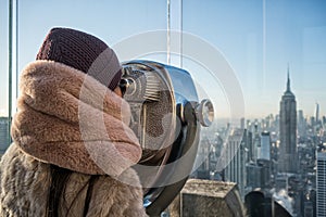 Young girl peeking through tourist binoculars with reflection of new york city.