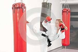 Young girl performing martial arts high kick boxing heavy bag.