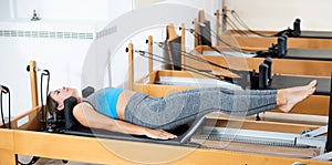 Young girl performing pilates exercises on reformer in studio photo