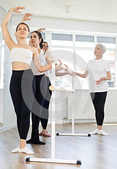 Young girl performing third position at ballet barre