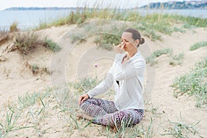 Young girl performs morning breathing practices of pranayama Nadi Shodhana on the beach in summer photo
