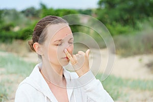 Young girl performs morning breathing practices of pranayama Nadi Shodhana on the beach in summer