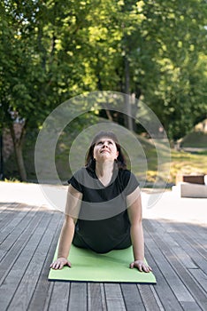 Young girl performs a yoga pose dog looking up. Outdoor exercise. Yoga for beginners. Beautiful woman, dog face up asana