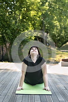 Young girl performs a yoga pose dog looking up. Outdoor exercise. Yoga for beginners. Beautiful woman, dog face up asana