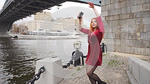 Young girl with a phone in hand is dancing on waterfront
