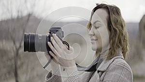 Young girl photographer. Action.A beautiful young girl who shoots on a professional camera in a gray gloomy cold weather