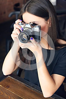 Young girl photographer with old analog camera in cafe