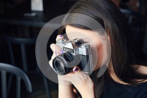 Young girl photographer with old analog camera in cafe