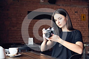 Young girl photographer with old analog camera in cafe