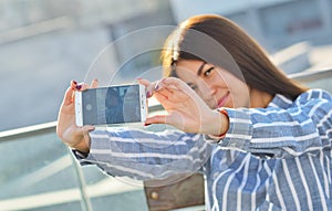 A young girl photographs herself with a phone