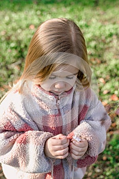 Young girl picking a delicate flower in a lush green field under the warm sun