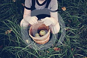 A young girl picking up some apples