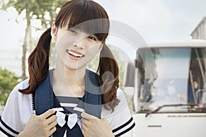 Young Girl in Pig Tails in School Uniform Commuting to School, Looking At Camera