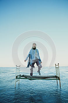 Young girl with pigtails in old clothes jumping on an old bed on