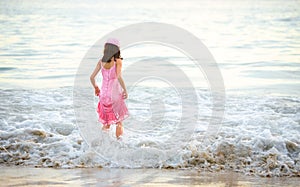 Young girl in pink dress enjoying the waves