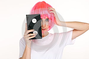 Young girl in the pink wig closing her eye by an old cassette.