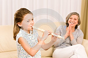 Young girl play flute with proud grandmother