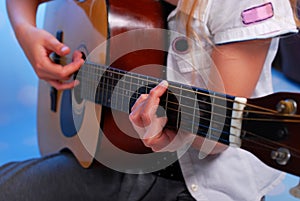 Young girl playing acoustic guitar on the stage