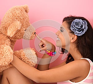 Young girl playing with big teddy bear